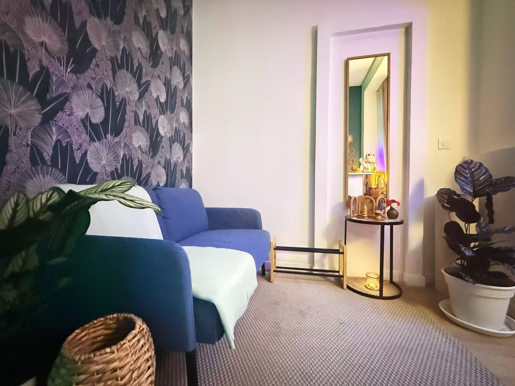 Une pièce bien éclairée avec un canapé, un bureau de réception et du papier peint décoratif.