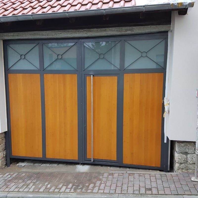 Holzgaragentore mit grauen Glasscheiben an einer Backstein- und Stuckfassade