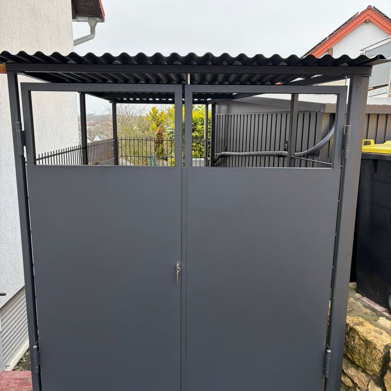 Graues Metalltor mit Wellblechdach in einem schmalen Außendurchgang