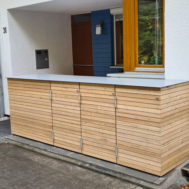 Hausfassade mit heller Holzvertäfelung, weißem Dachüberstand und einer blauen Fensterfront mit gelben Zierleisten