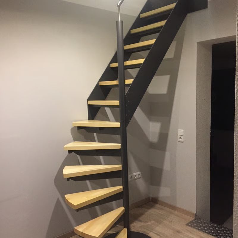 Geschwungene, freitragende schwarze Treppe mit hellen Holzstufen in einer modernen Innenhalle