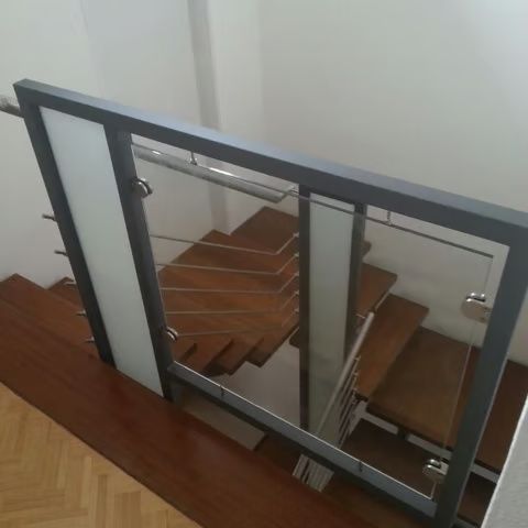 Treppe mit Holzstufen und einem Geländer aus Glas und Metall in einem modernen Interieur.