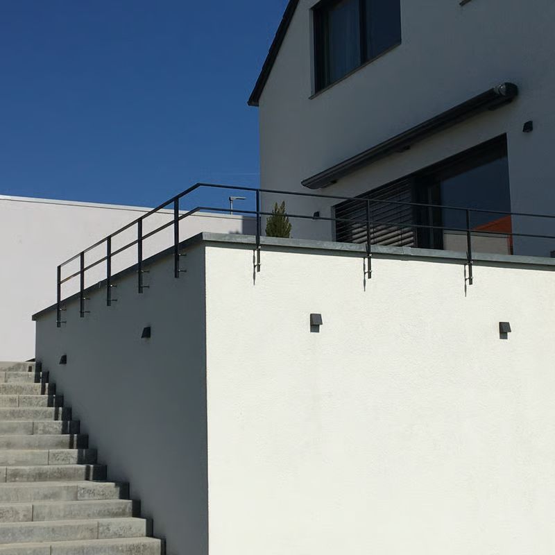 Modernes weißes Gebäude mit schwarzen Geländern und Betontreppen unter klarem blauen Himmel