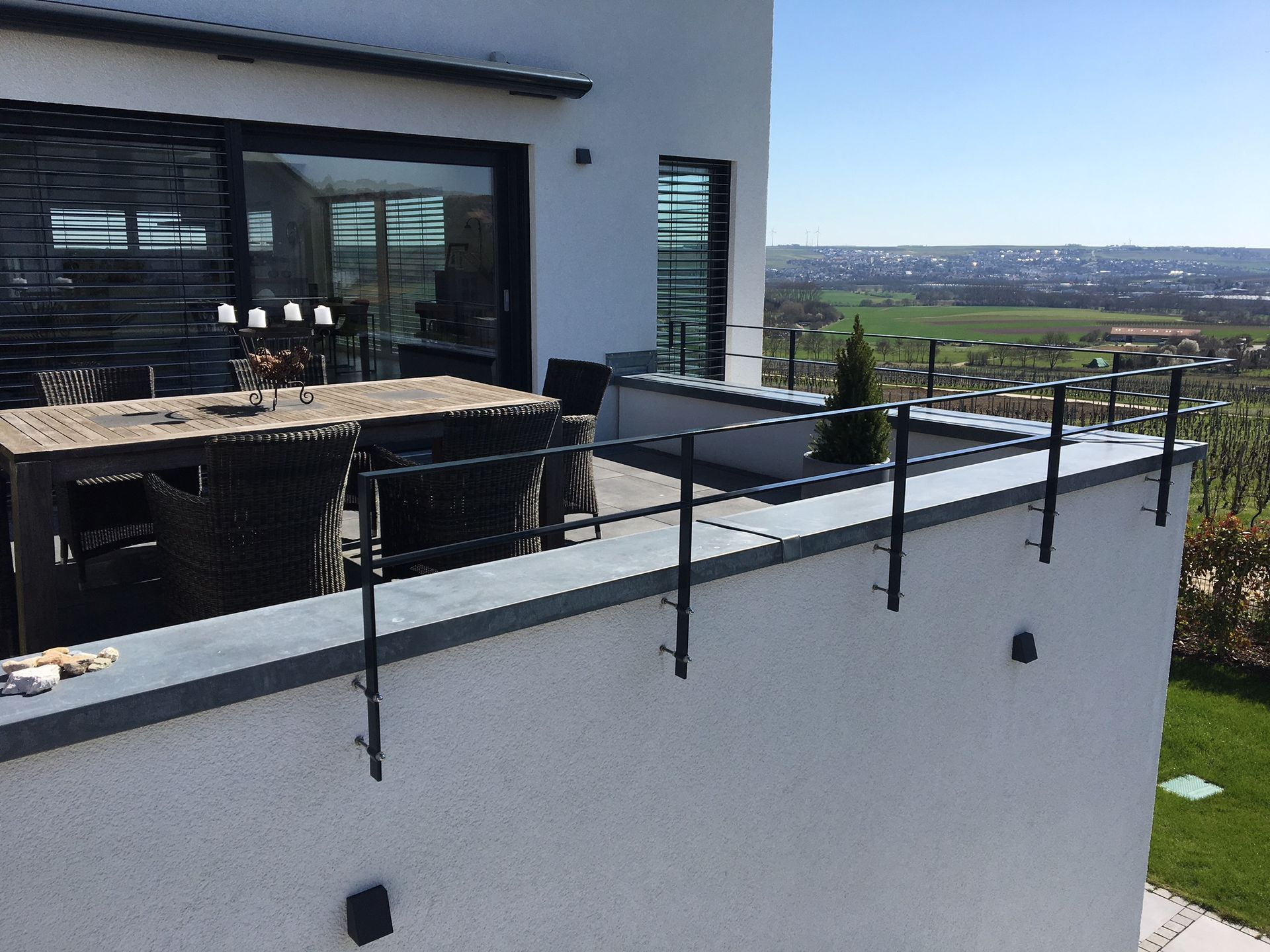 Moderne Hausterrasse mit schwarzem Geländer, Sitzgelegenheiten im Freien und Blick