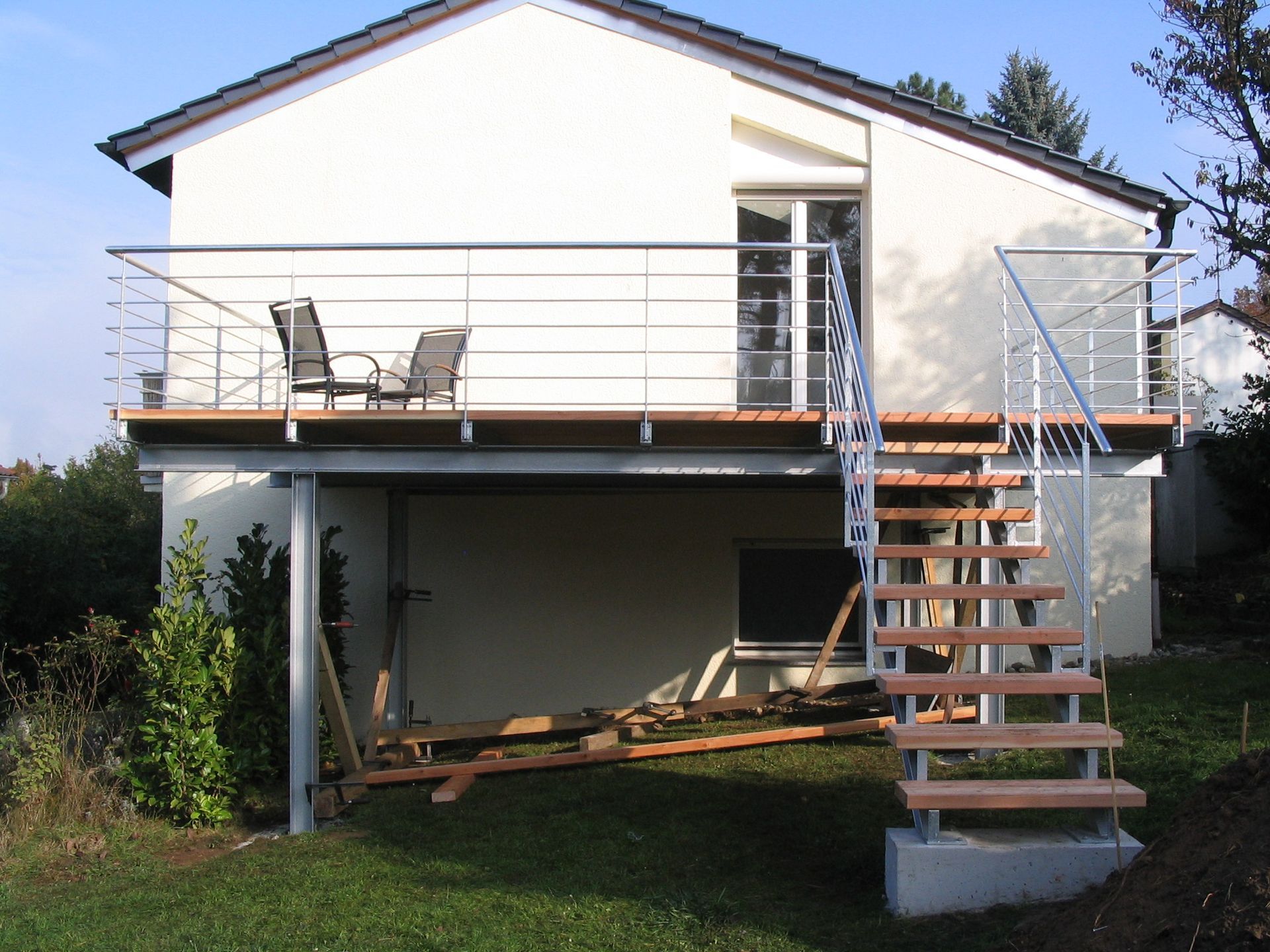 Modernes Haus mit erhöhter Terrasse und Außentreppe über einem unausgebauten Untergeschoss