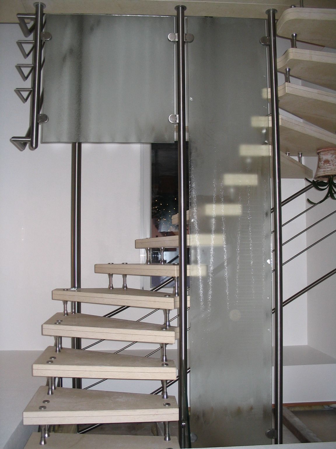 Wendeltreppe mit Holzstufen und Metallgeländer neben einer Glaswand