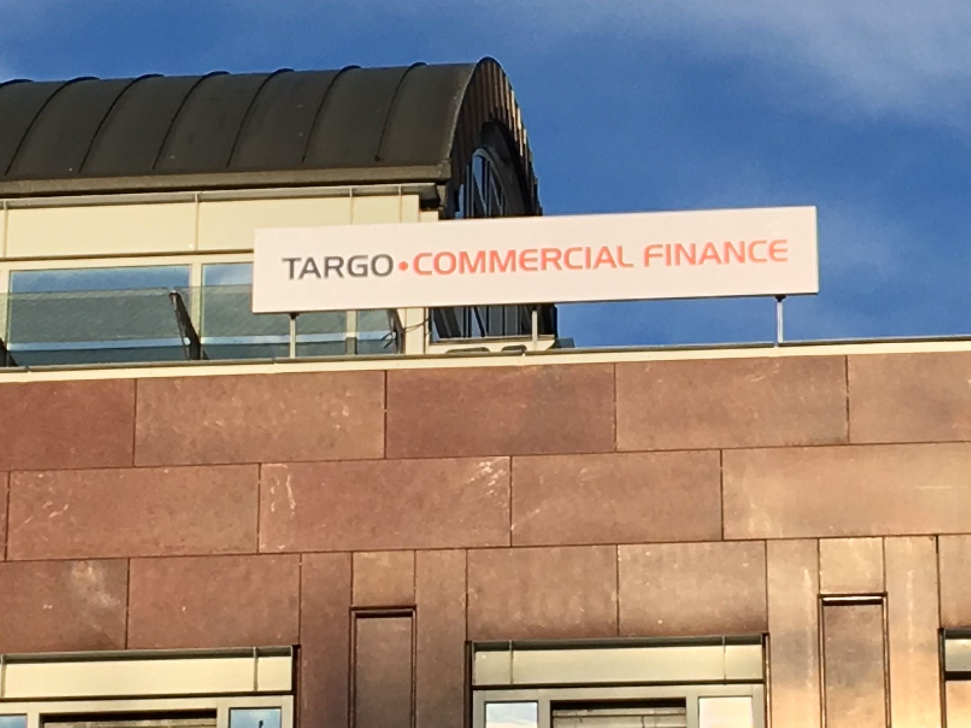 Das Schild von Targo Commercial Finance prangt an einem braunen Gebäude unter blauem Himmel.