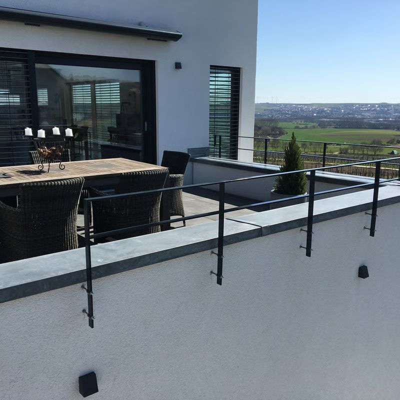 Moderne Terrasse mit Esstisch und Stühlen, von der aus man einen malerischen Blick über ein Tal genießt.