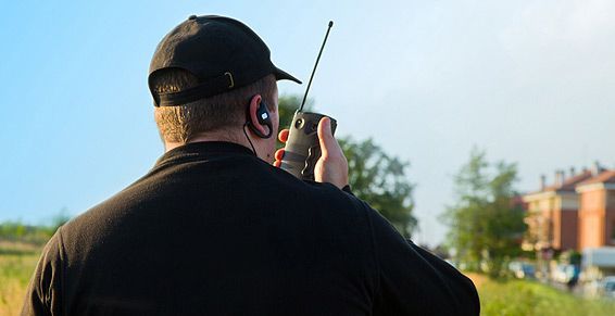 Caméra de sécurité extérieure, blanche avec objectif noir, sur fond d'arbre et de ciel flous.