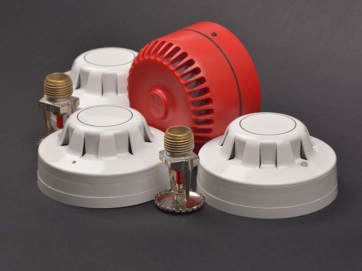 Des sprinklers et une alarme incendie rouge sur fond sombre.