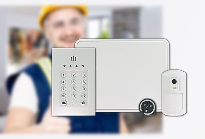 Composants d'un système de sécurité avec l'installateur en arrière-plan flou. Clavier blanc, panneau de commande et détecteur de mouvement.