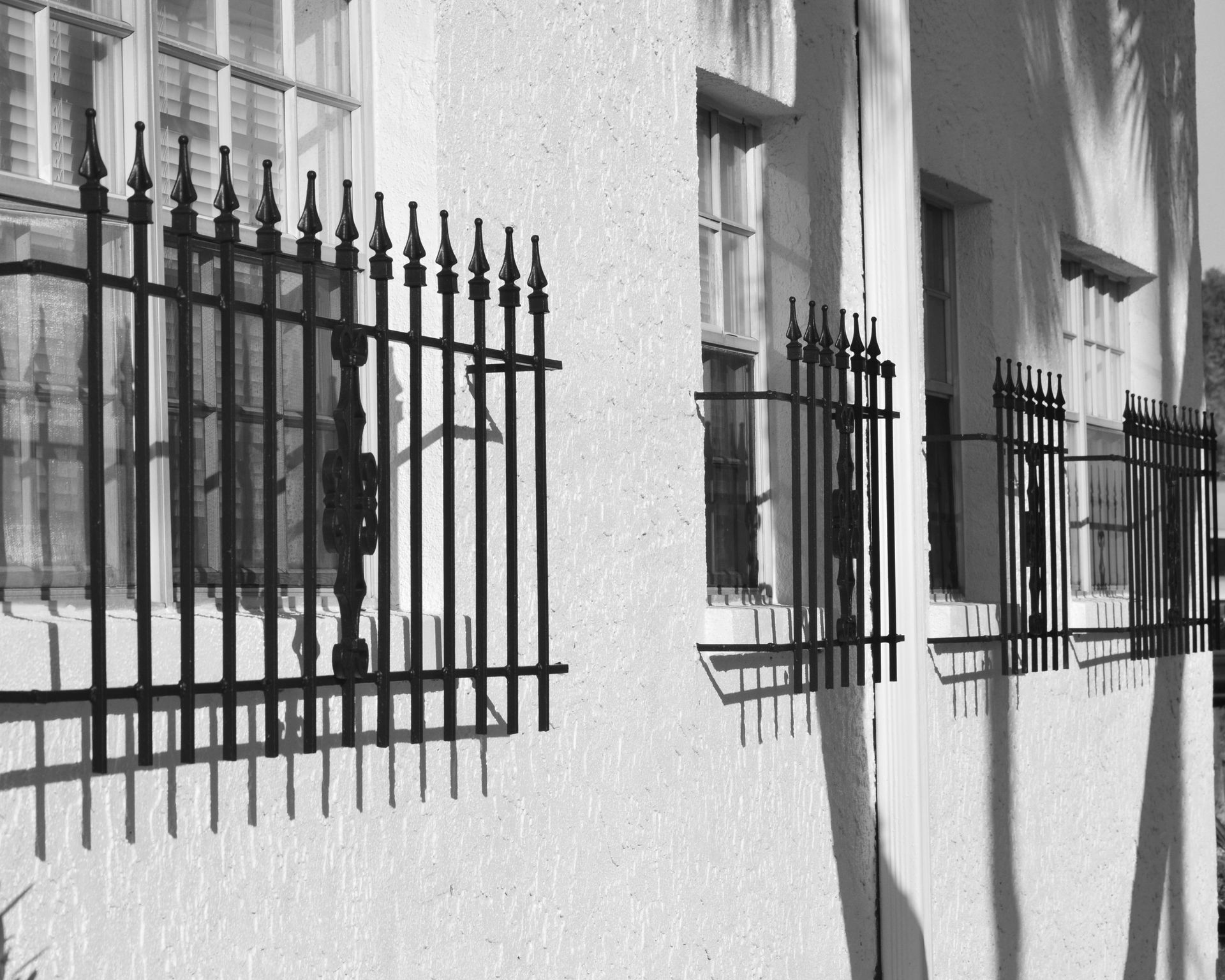 Fenêtre ouverte grilles de défense noires et cadre en pierre sur un mur en pierre.