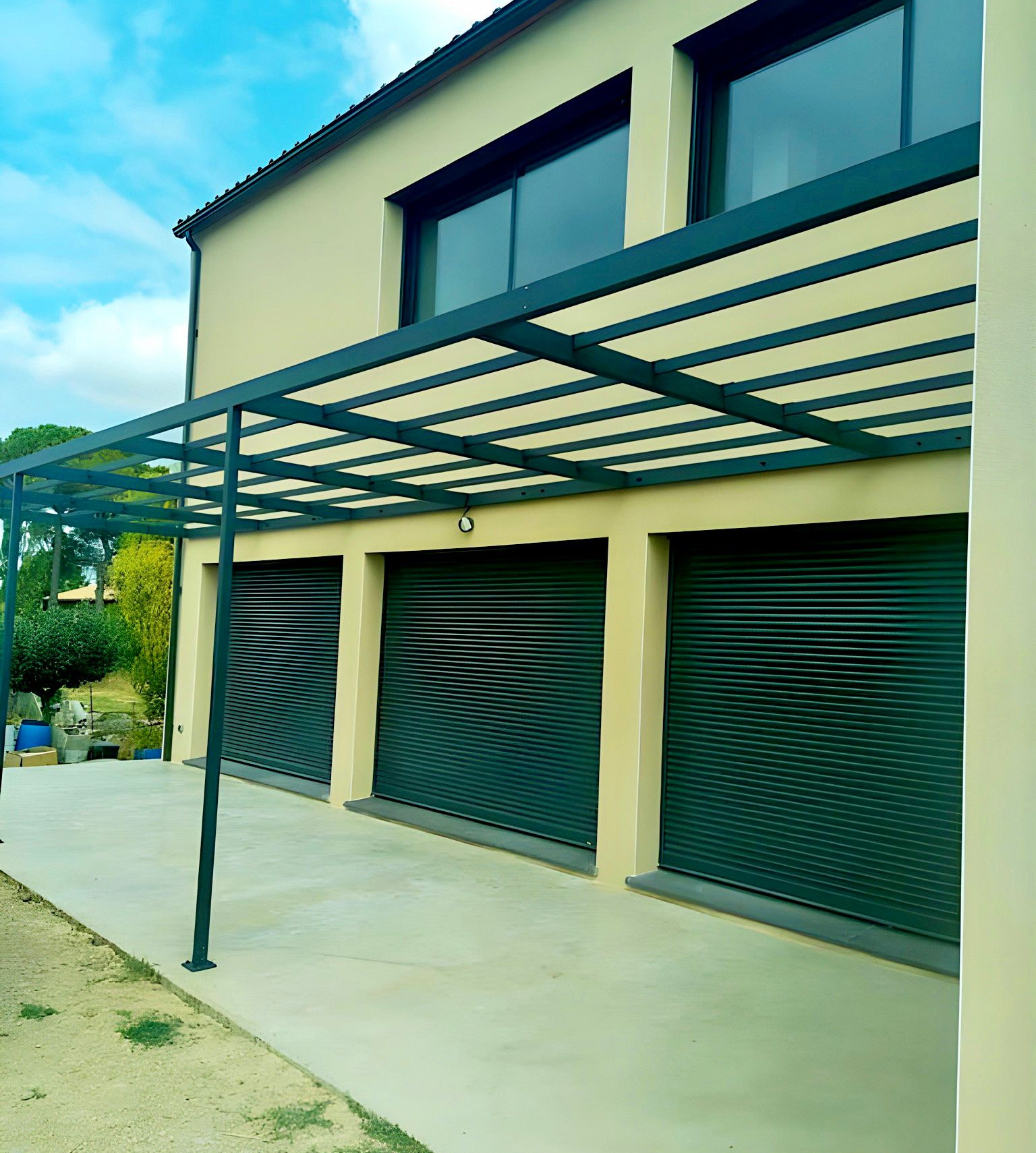 Pergola en acier, vue extérieure d'une maison, une terrasse et des volets roulants gris anthracite.