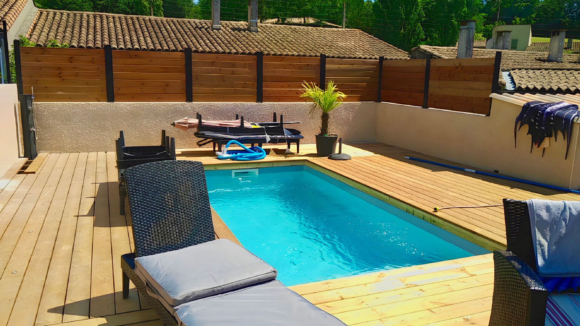 Clôture métallique avec remplissage en bois style persienne avec une piscine.