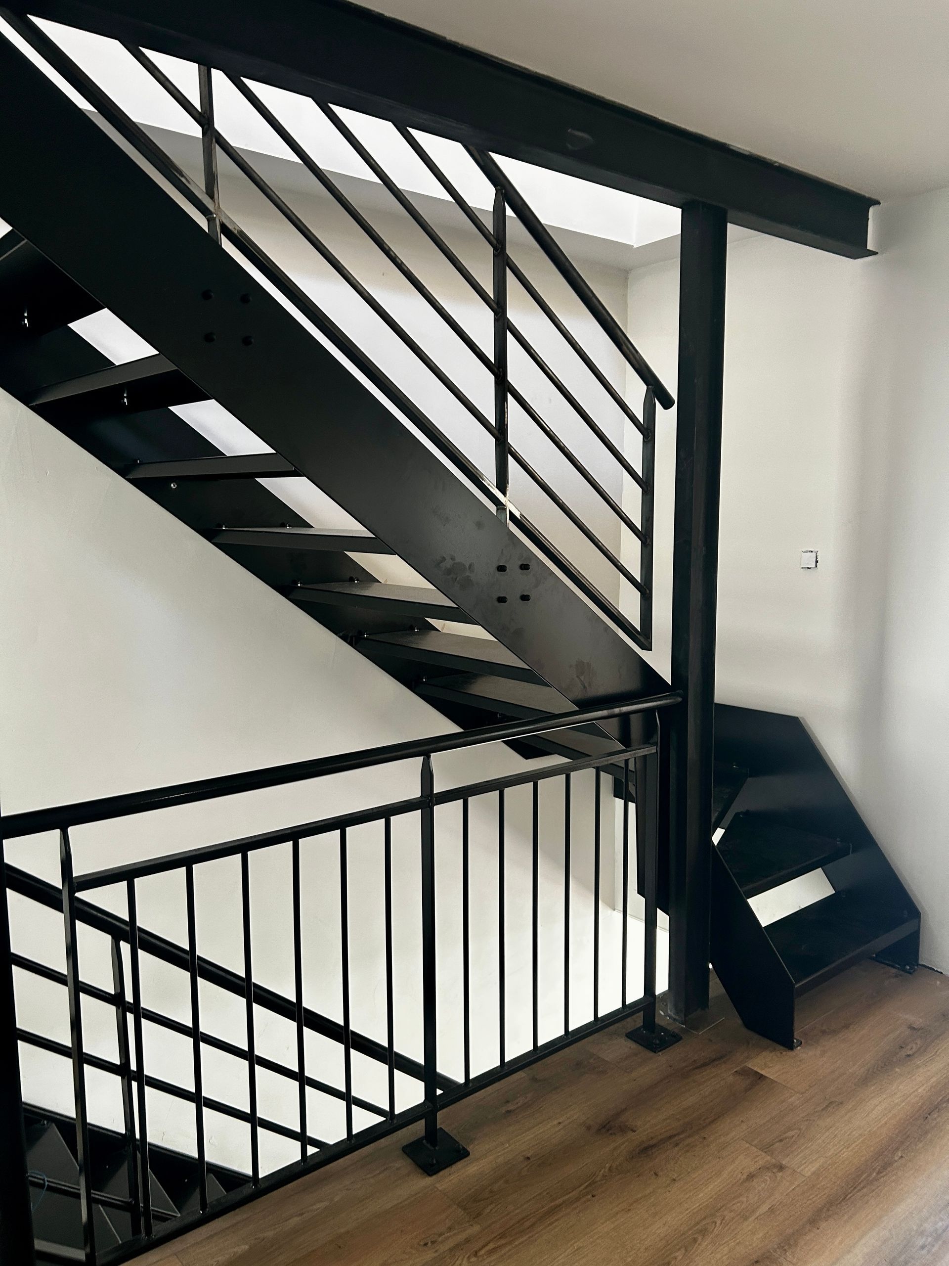 Escalier intérieur en acier noir avec garde corps métallique.