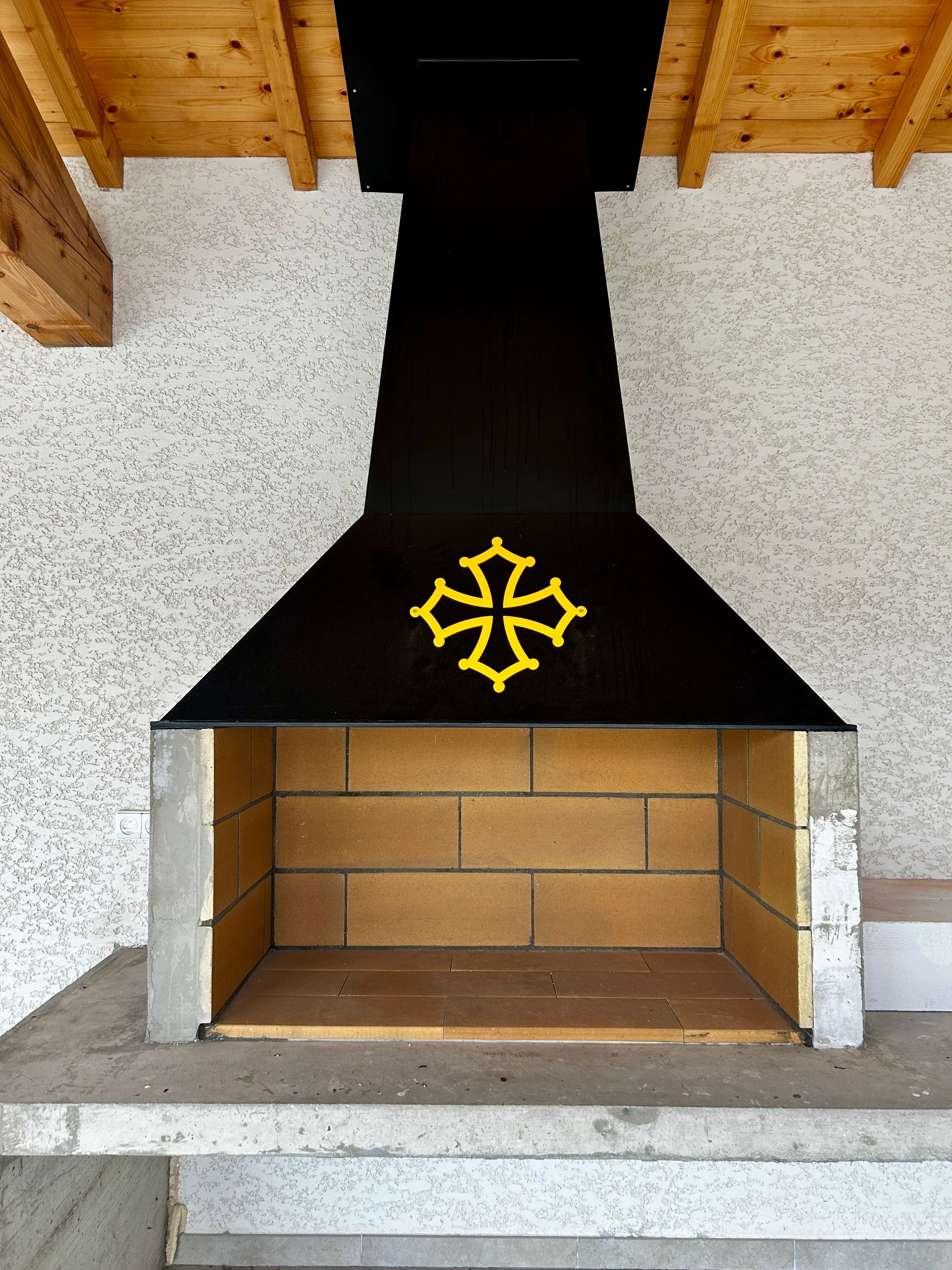 Hotte de barbecue en acier noire avec croix occitane orange.
