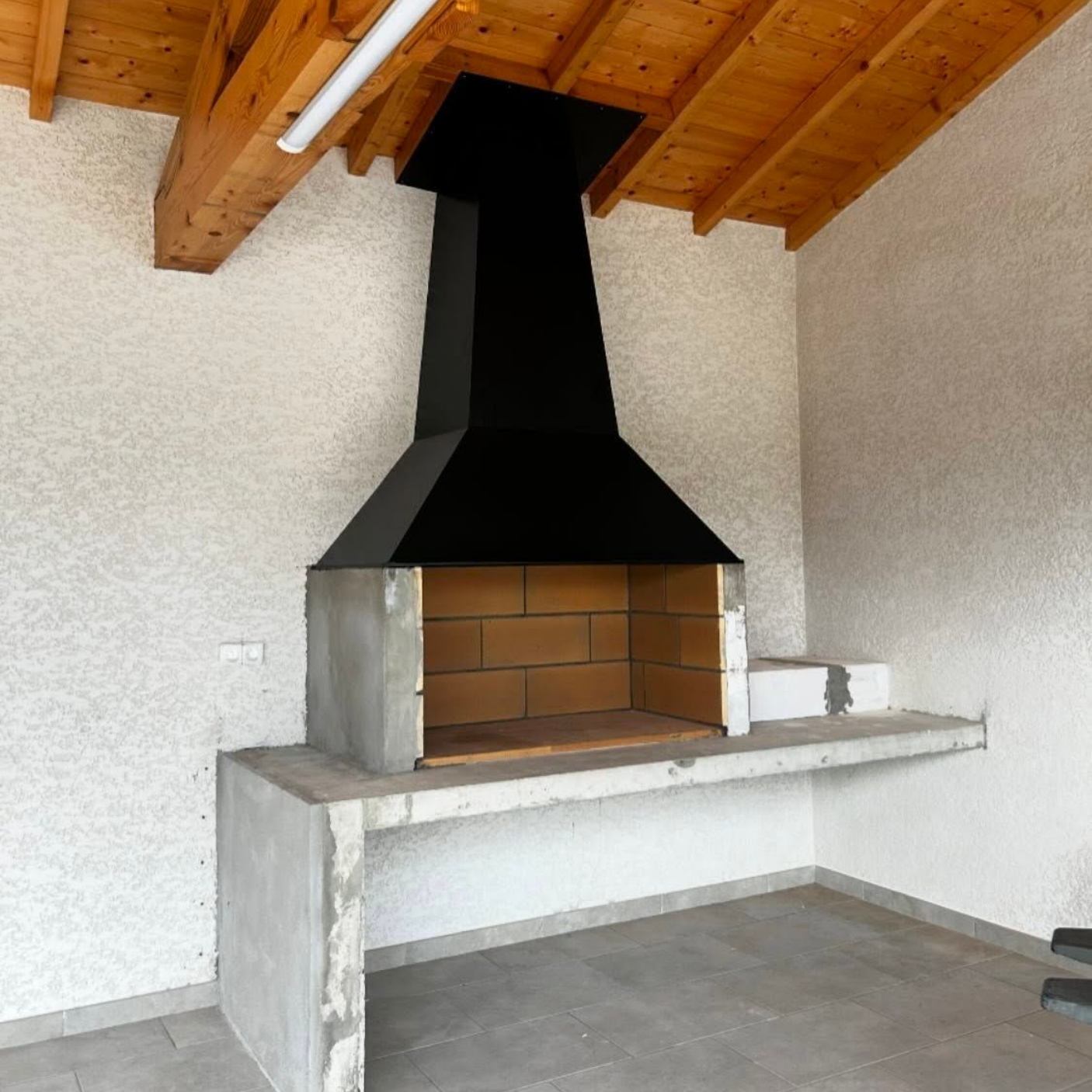 Barbecue extérieur en briques avec cheminée noire et comptoir en béton.