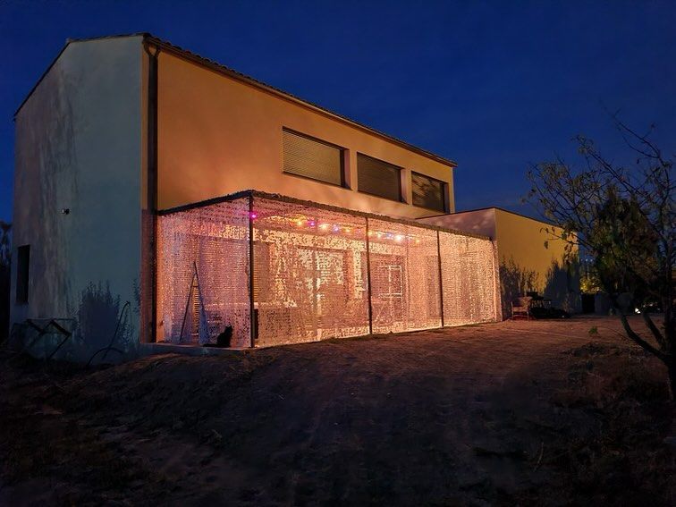 Bâtiment beige avec un patio clos et lumineux. Ciel bleu foncé au crépuscule.