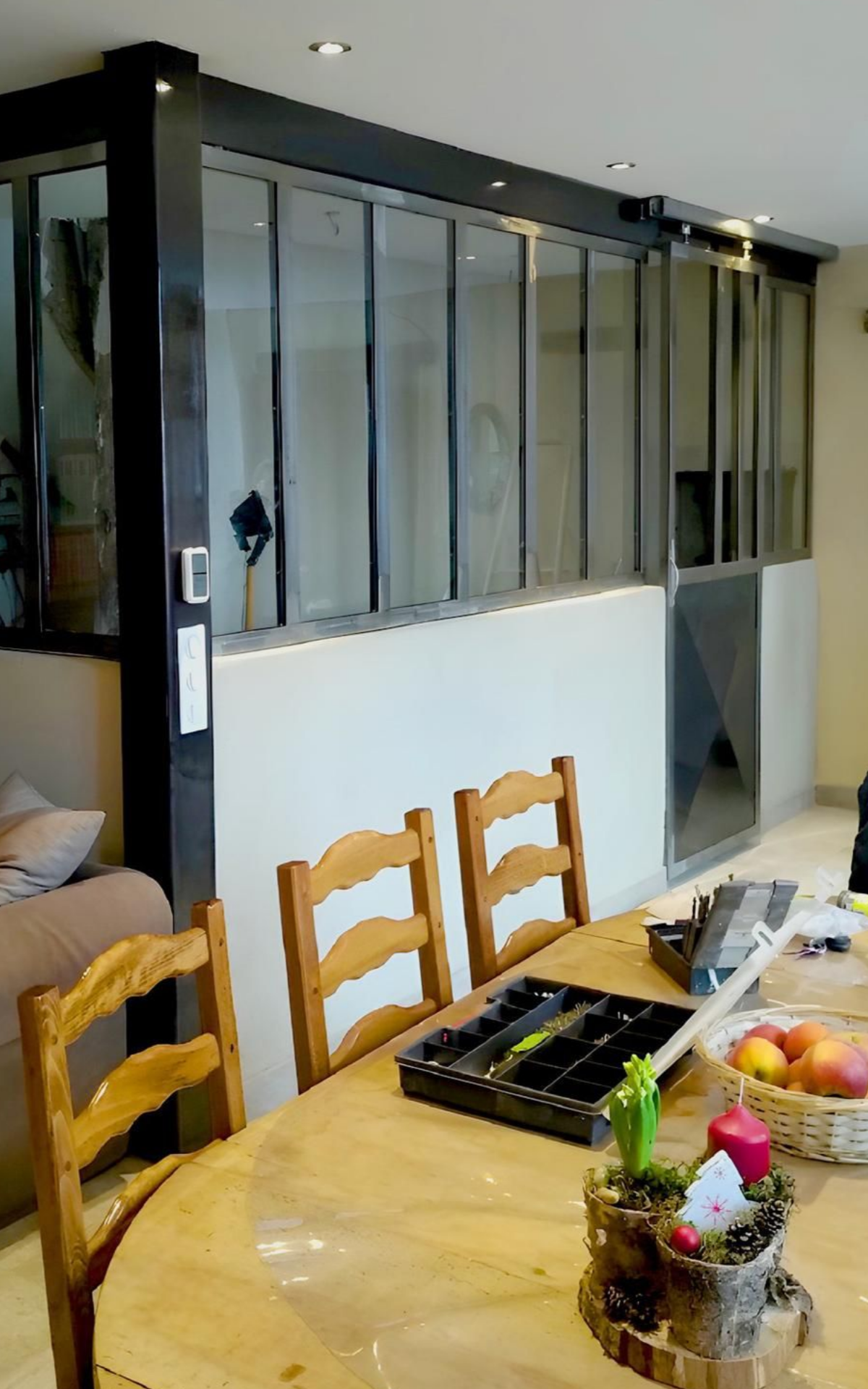 Intérieur avec paroi vitrée, table à manger, canapé et chaises.