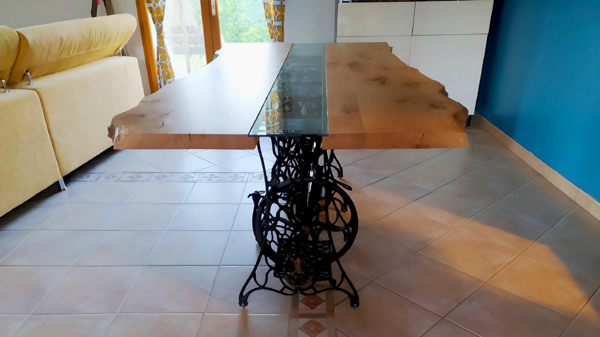 Table fabriquée à partir d'une dalle de bois avec incrustation d'époxy, soutenue par un socle de machine à coudre Singer antique noire.