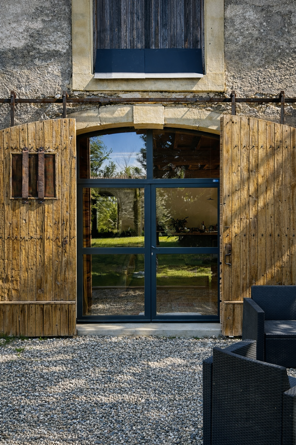 Vue extérieure d'un bâtiment avec des volets coulissants suspendus en bois et des portes en verre avec jardin.
