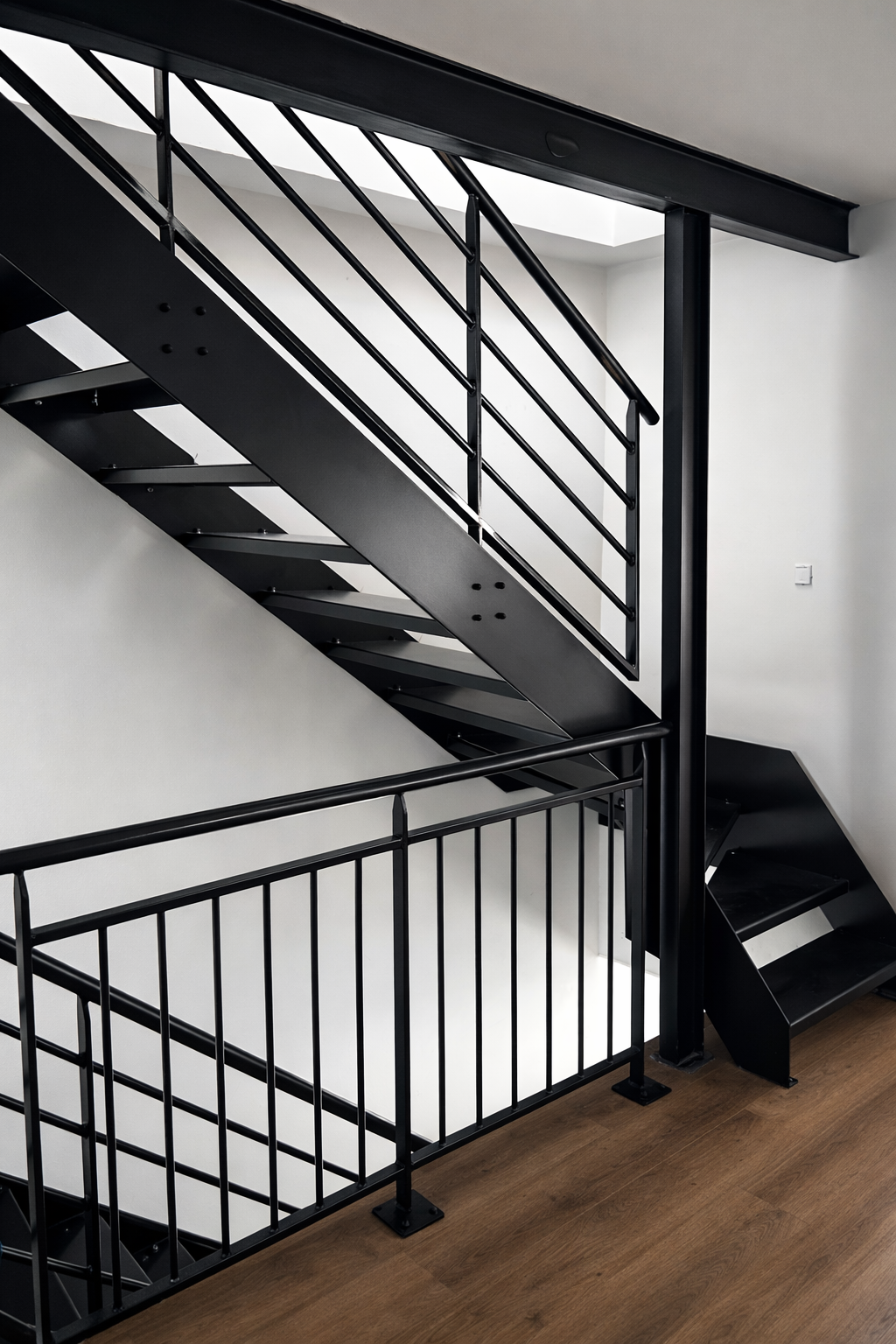 Escalier intérieur en acier noir avec garde corps métallique.