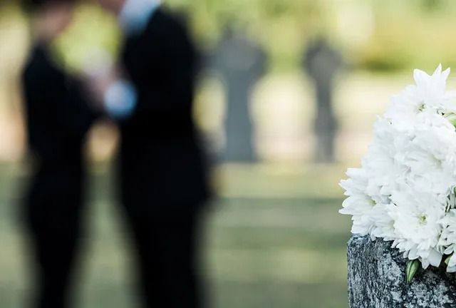 Un grupo de personas está de pie en un cementerio con flores en primer plano.