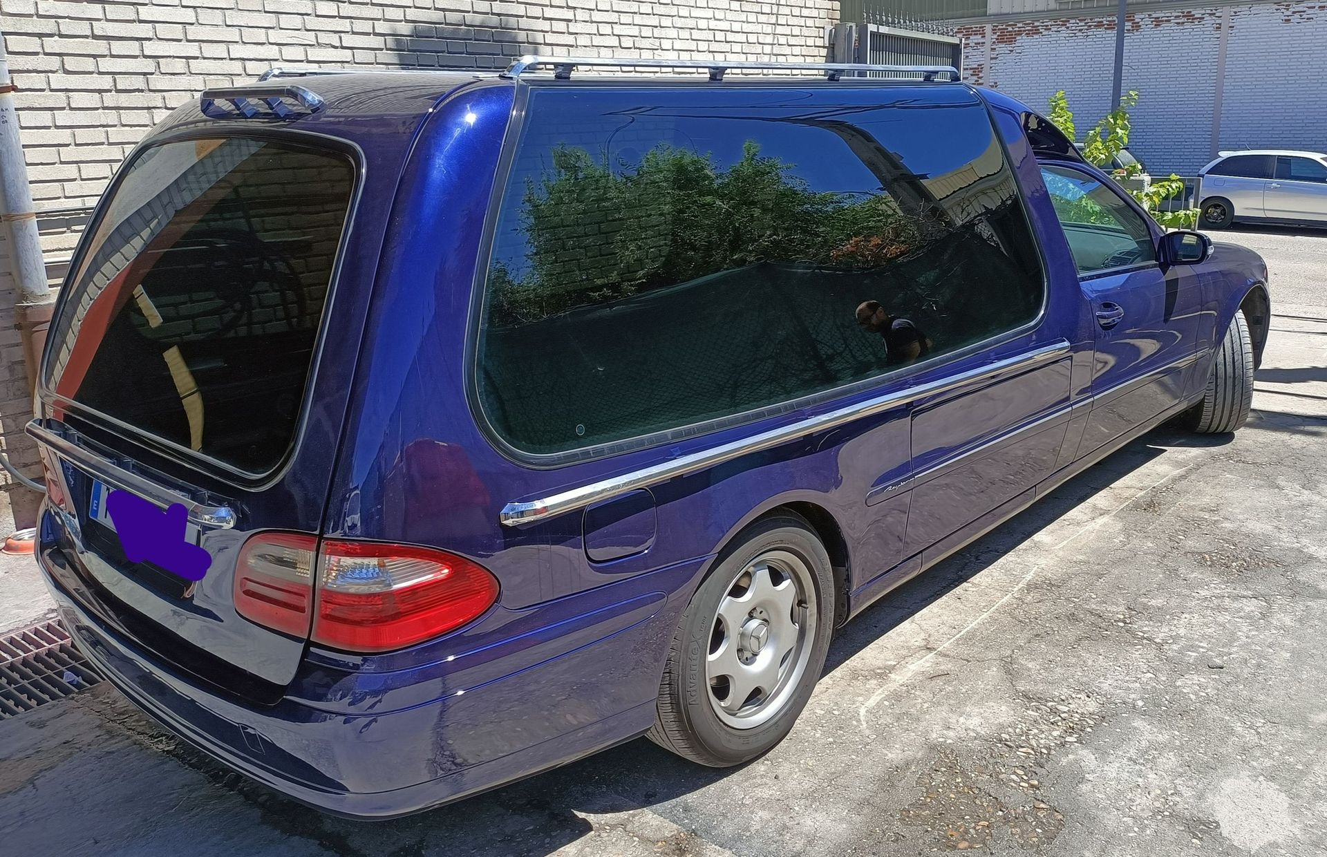 Un coche azul con matrícula morada está aparcado en un estacionamiento.