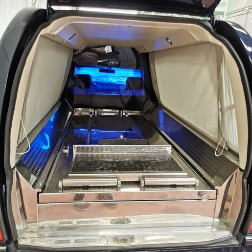 El interior de un vehículo funerario con el maletero abierto.