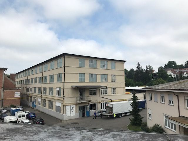 Ein großes Gebäude mit vielen Fenstern und davor geparkten Autos