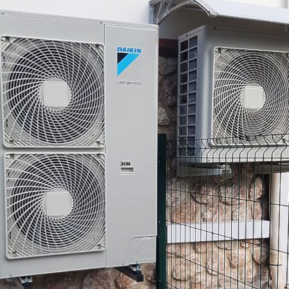 Deux unités de climatisation Daikin montées sur un mur en pierre, l'une avec deux ventilateurs et l'autre avec un seul ventilateur.