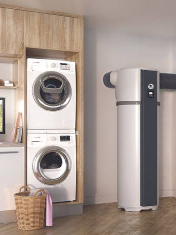 Laveuse et sécheuse blanches superposées avec un chauffe-eau blanc et gris dans une buanderie.