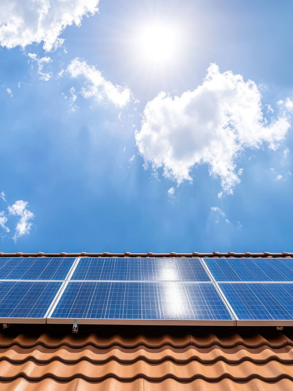 Des panneaux solaires sur un toit de tuiles rouges, sous un soleil éclatant.