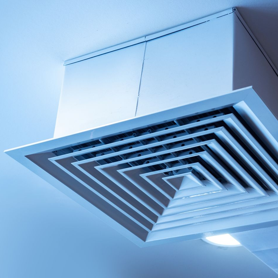 Grille d'aération de plafond blanche à motif carré et superposé, sur fond de plafond bleu.