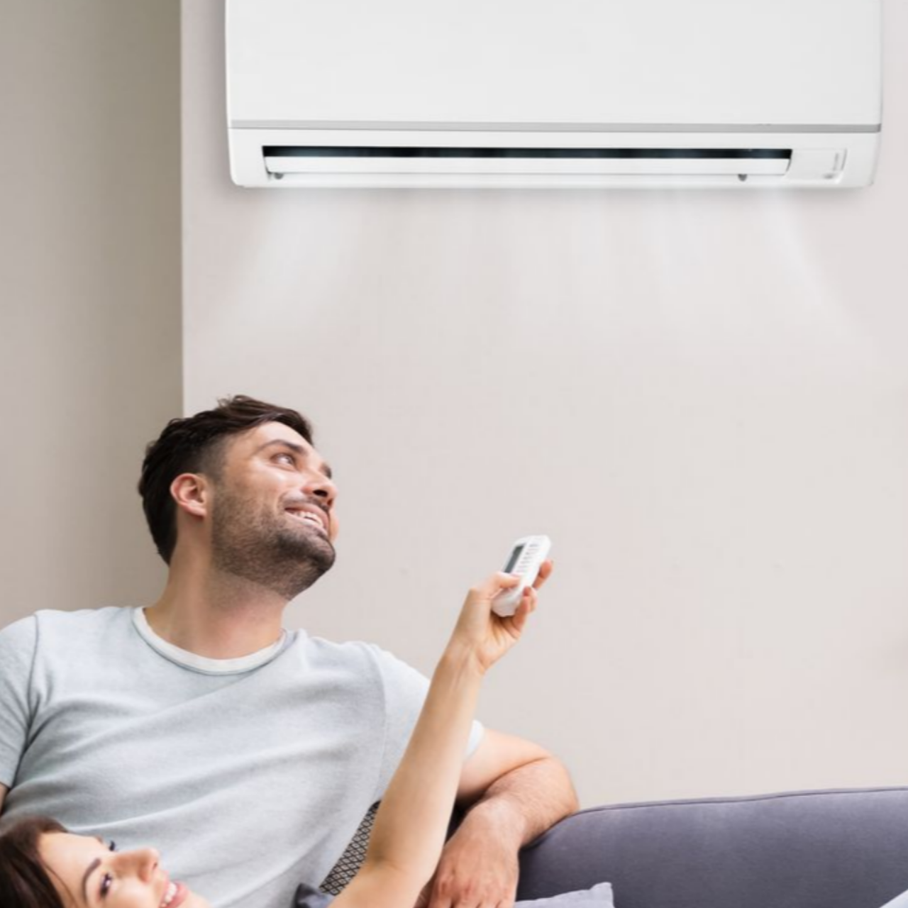 Un couple se détend en utilisant une télécommande pour contrôler un climatiseur.
