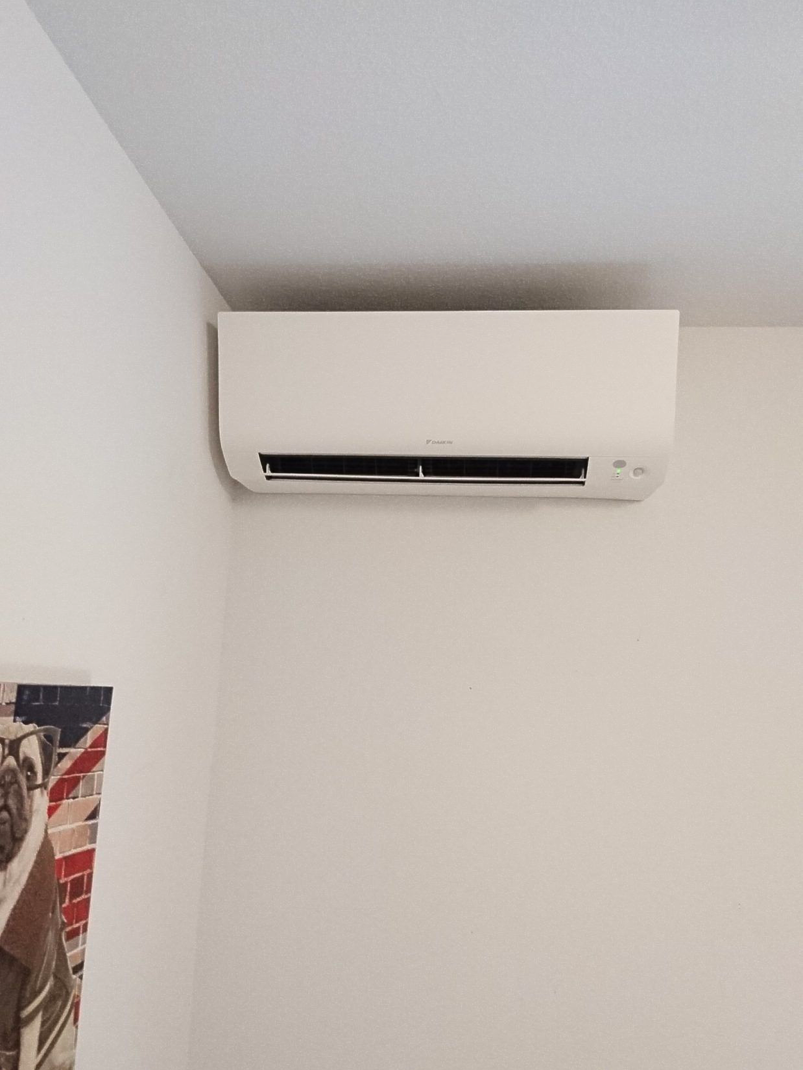 Unité de climatisation blanche fixée sur un mur blanc dans un coin.