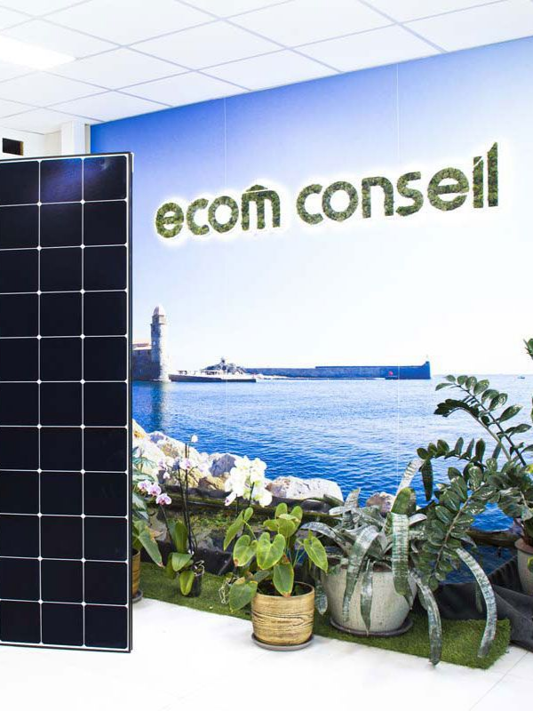 Panneau solaire dans une salle d'exposition avec le logo « ecom conseil » et un paysage marin en arrière-plan.