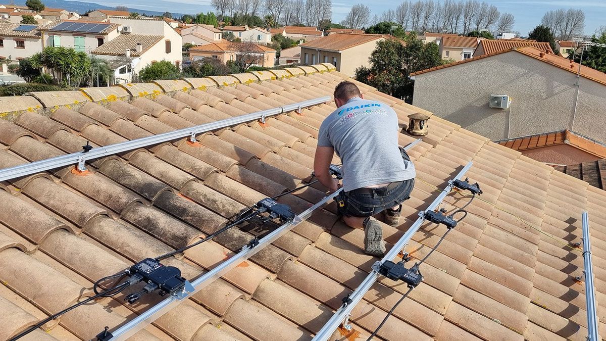 Une personne installant des panneaux solaires sur un toit en tuiles.