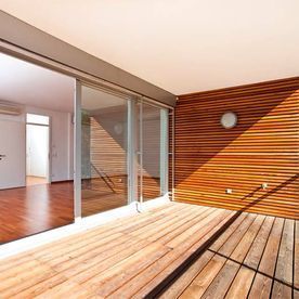 Una terraza de madera con puertas corredizas de vidrio y una pared de madera.