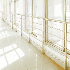 Un pasillo largo con muchas ventanas y una barandilla de metal.