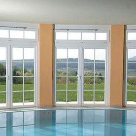 Una gran piscina cubierta con muchas ventanas y vistas a un campo.