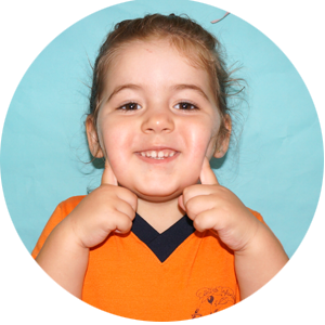Una niña con una camiseta naranja está haciendo un gesto de aprobación con el pulgar hacia arriba.