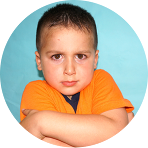 Un niño con los brazos cruzados lleva una camiseta naranja.