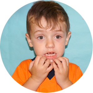 Un niño con una camisa naranja se cubre la boca con las manos.