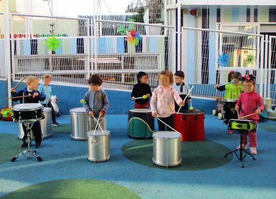Un grupo de niños está tocando la batería en un patio de recreo.