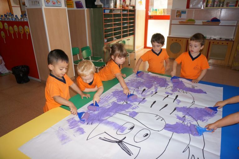 Un grupo de niños está pintando en un trozo grande de papel.
