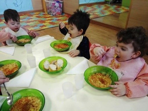 Un grupo de niños está sentado en una mesa comiendo comida.