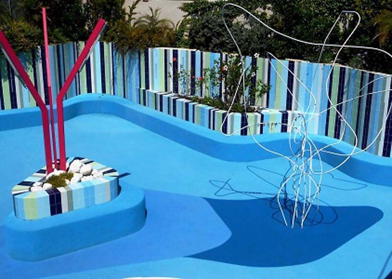 Una piscina azul con una valla rayada al fondo.