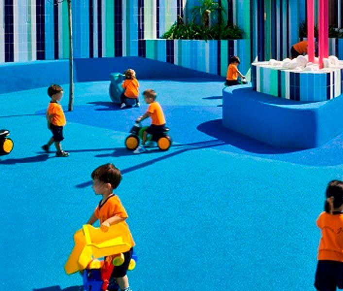 Un grupo de niños está jugando en un patio de recreo azul.