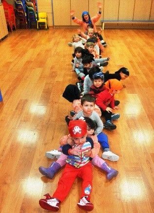 Un grupo de niños están acostados en el suelo en fila.